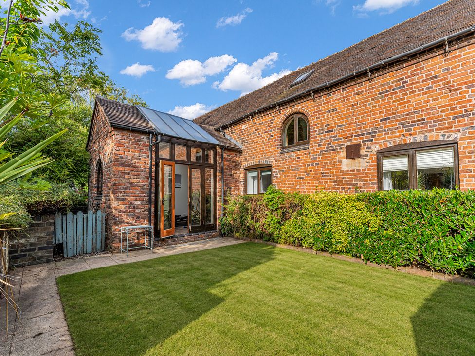 A garden with brick walls and a glass door at Oxhay Barn Newcastle