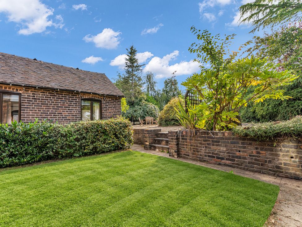 A garden with a brick house and green lawn at Oxhay Barn Newcastle