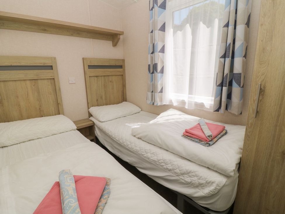 A bedroom with two beds and a wardrobe at Laughter Tor in Tavistock