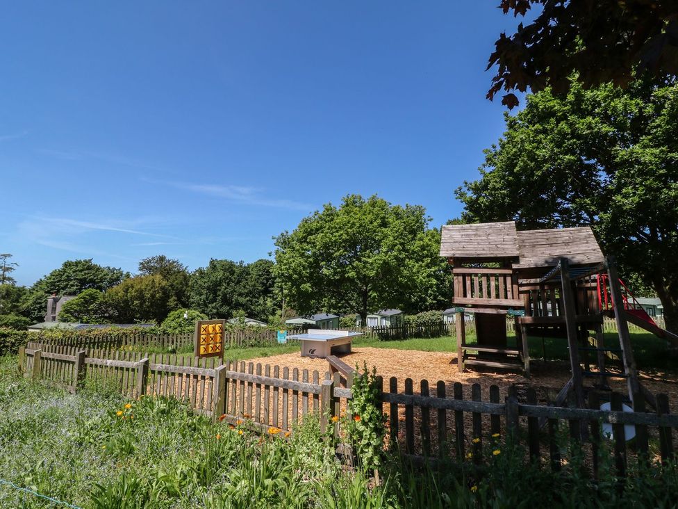 A playground with a play structure and sandbox at Laughter Tor Tavistock
