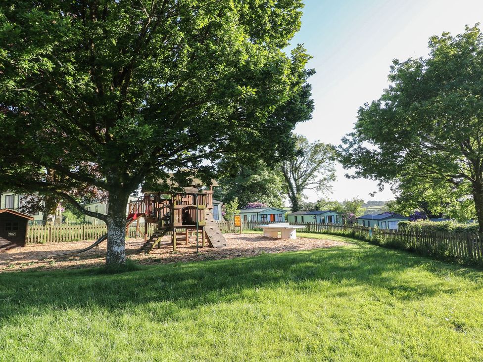 A garden with a playground and trees at Laughter Tor Tavistock