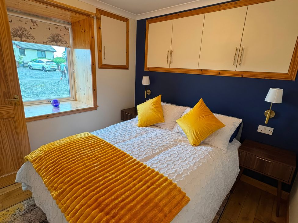 A bedroom with a bed and nightstands at Bothan Beag, Daliburgh, Isle Of South Uist