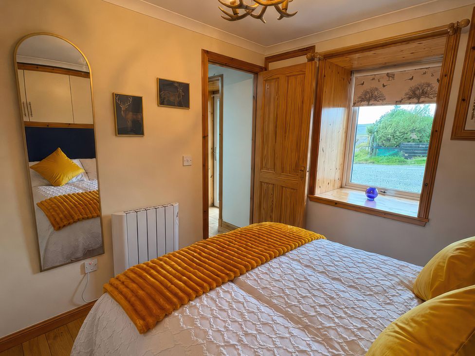 A bedroom with a bed, pillows, and a window at Bothan Beag, Daliburgh, Isle Of South Uist