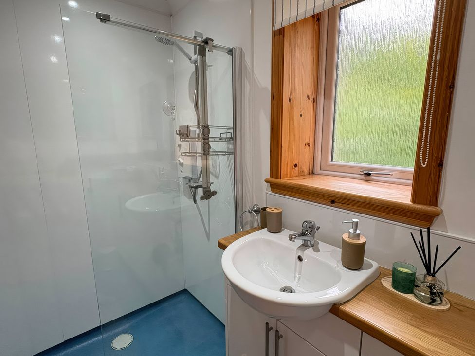 A bathroom with a shower and sink at Bothan Beag, Daliburgh, Isle Of South Uist