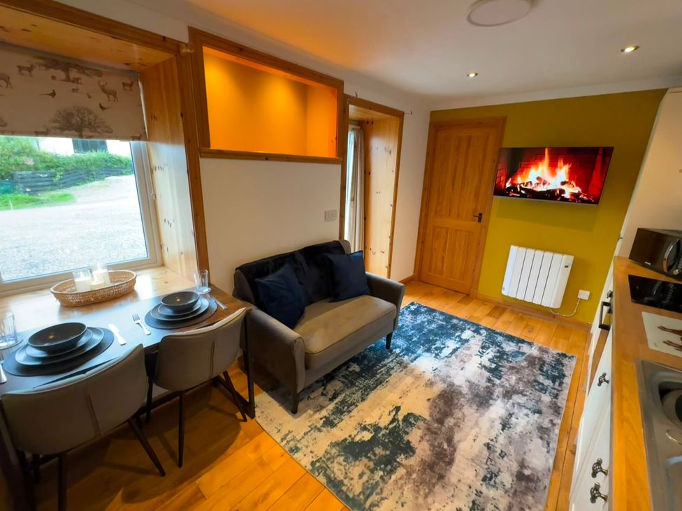 A living room with table, chairs, and a sofa at Bothan Beag in Daliburgh, Isle Of South Uist