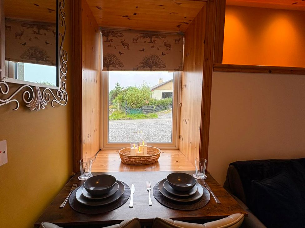 A dining area with a table set for two at Bothan Beag Daliburgh, Isle Of South Uist