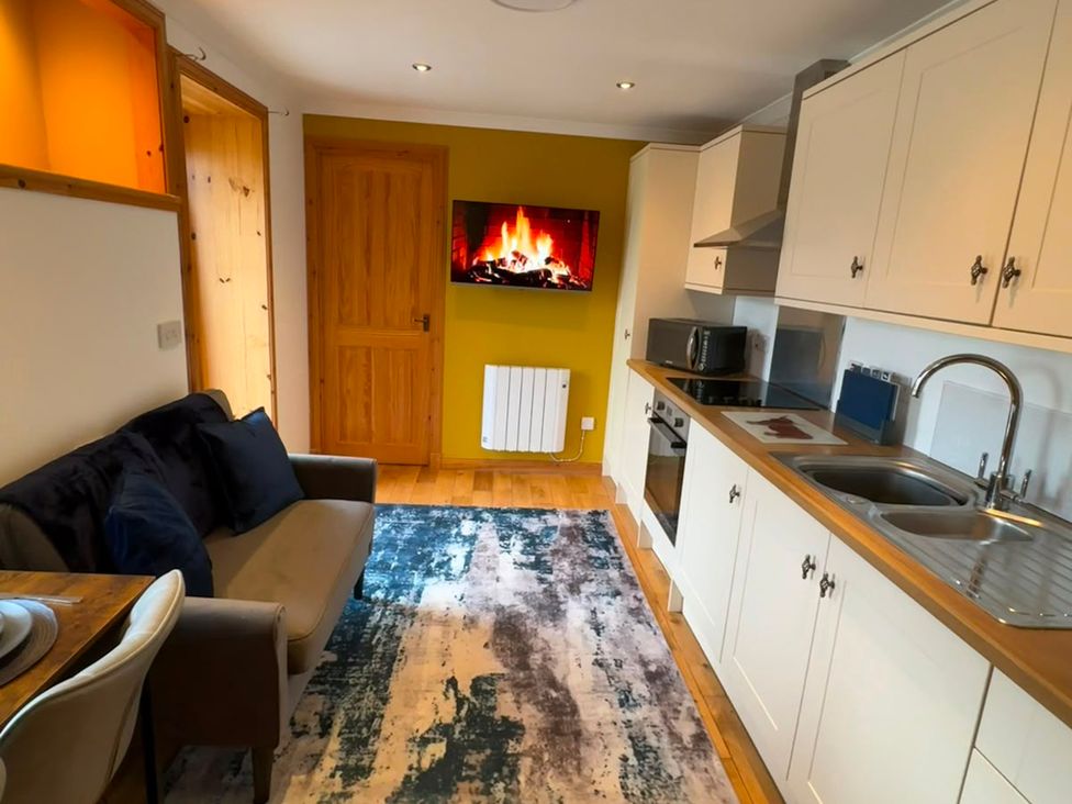 A kitchen with a sofa and dining table at Bothan Beag, Daliburgh, Isle Of South Uist