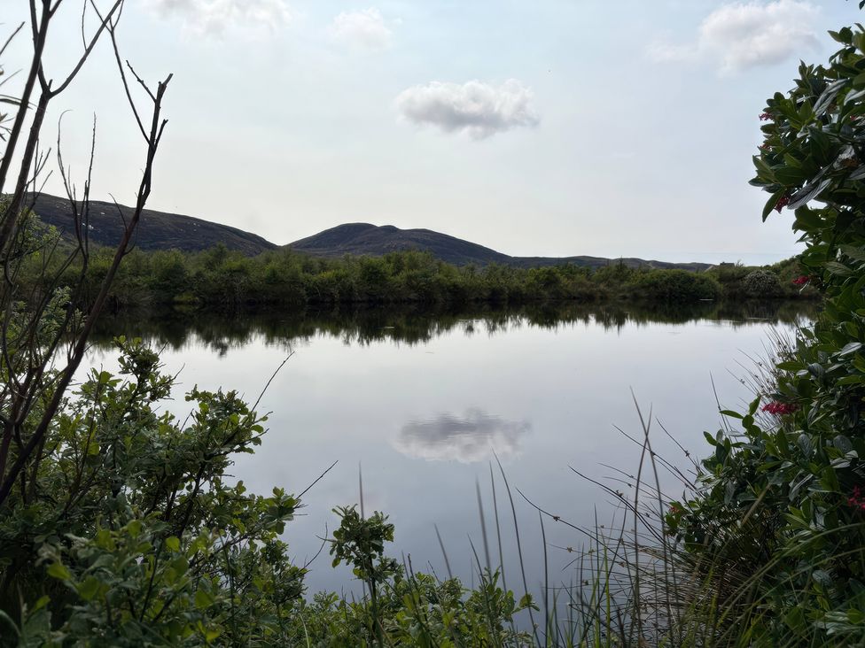 A view of water reflecting mountains and vegetation at Bothan Beag in Daliburgh, Isle Of South Uist