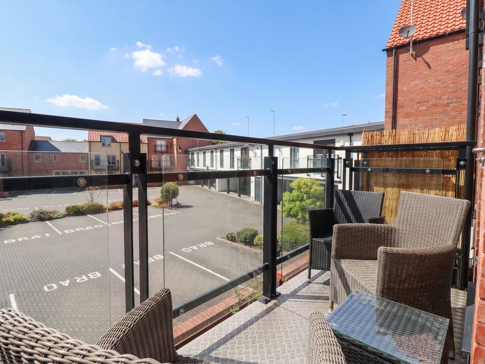 A balcony with chairs and a table overlooking a parking lot at Blanket Row in Hull