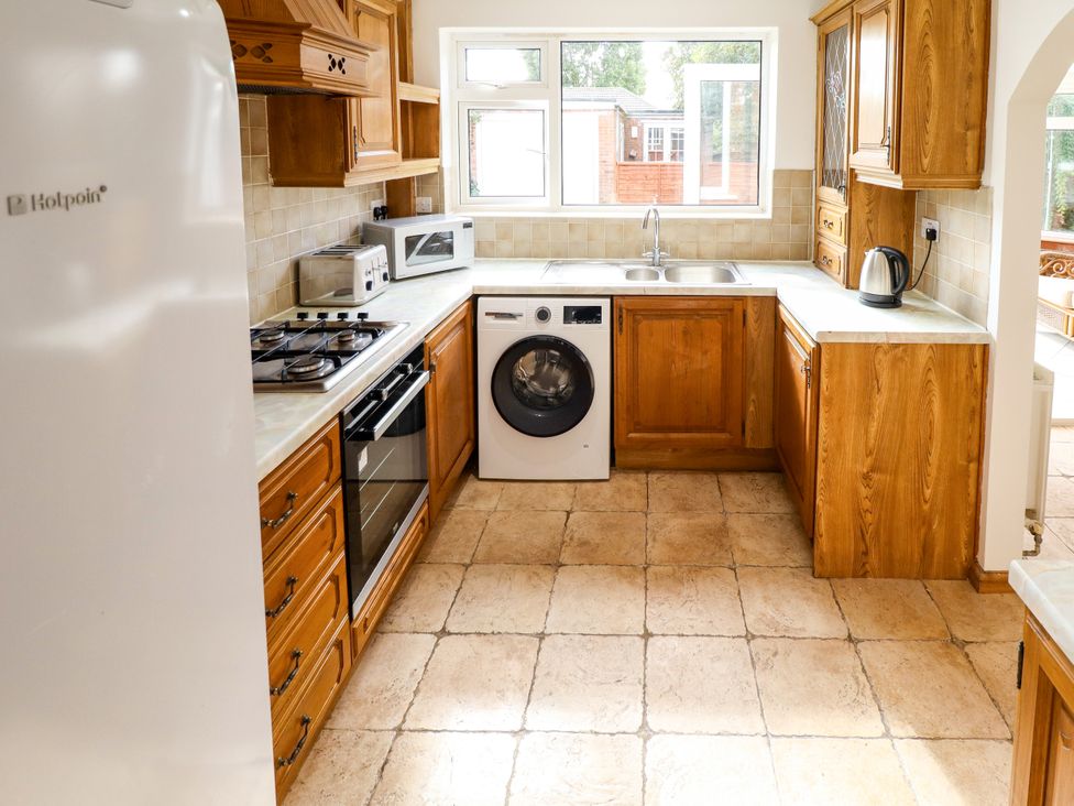 A kitchen with appliances and wooden cabinets at Mariner's Nook in Cleethorpes