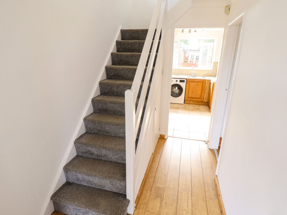 A hallway with carpeted stairs and a view of the kitchen at Mariner's Nook in Cleethorpes
