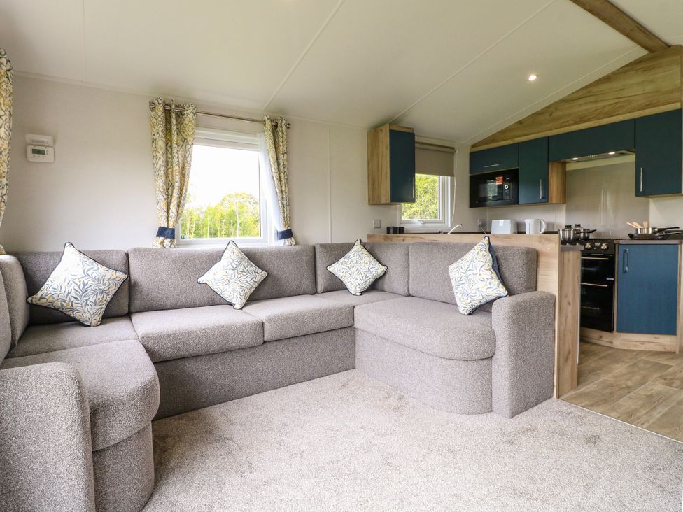 A living room with a corner sofa and kitchen units at Kestrel Lodge in Coalville