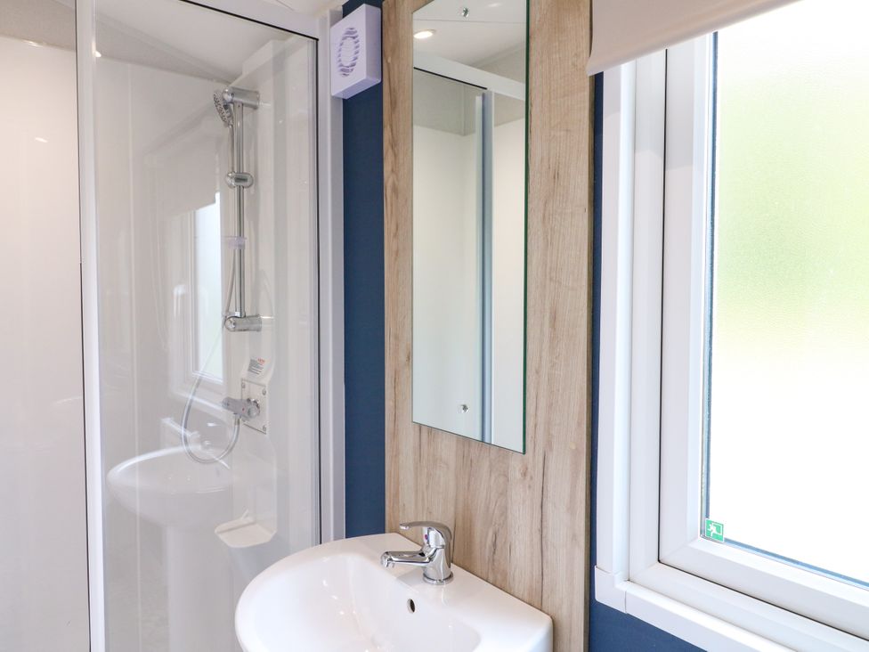 A bathroom with a shower, sink, and mirror at Kestrel Lodge in Coalville