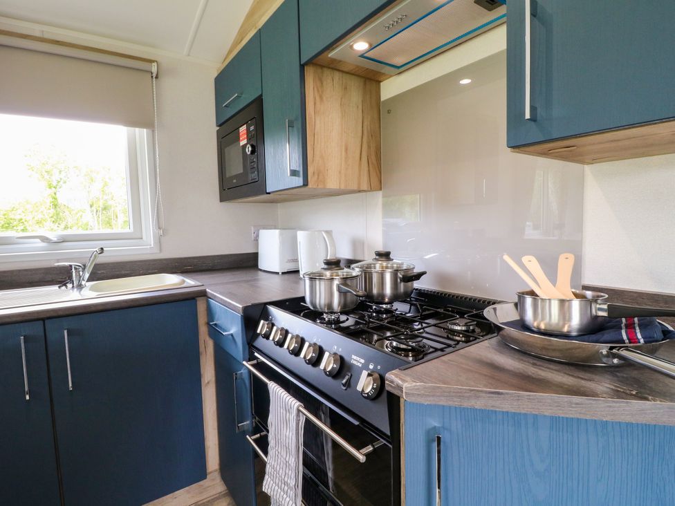A kitchen with pots on the stove and a microwave at Barn Owl Lodge Coalville