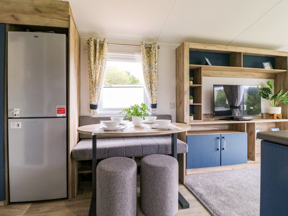 A kitchen with a refrigerator, table and chairs at Red Kite Lodge in Coalville