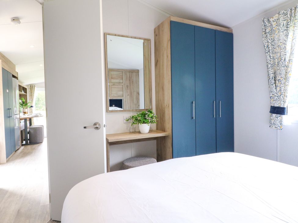 A bedroom with a wardrobe and a mirror at Red Kite Lodge in Coalville