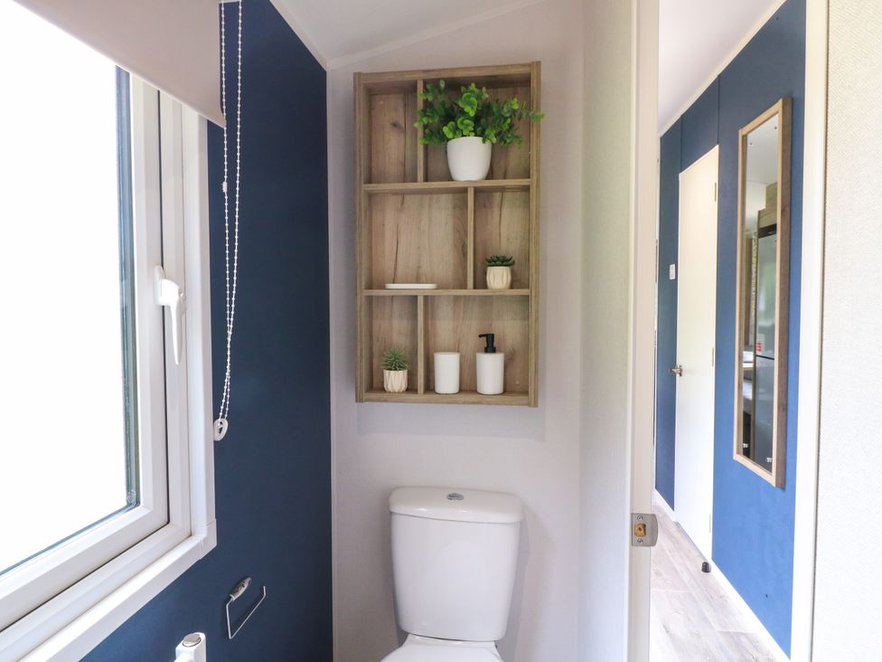 A bathroom with a toilet and a shelf with plants at Red Kite Lodge in Coalville