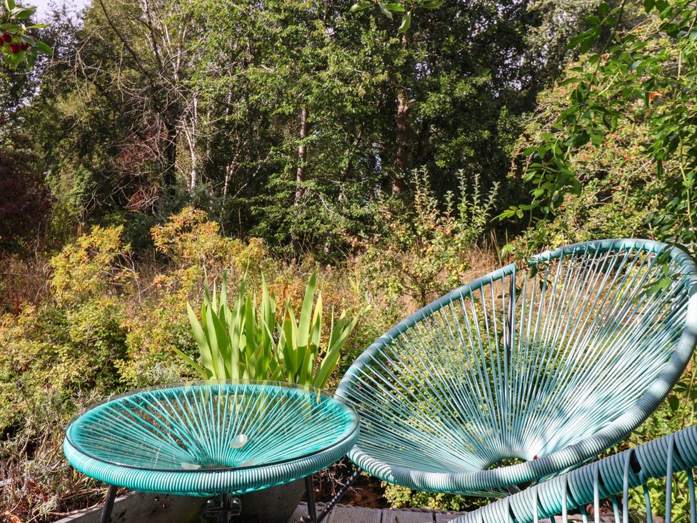 Two teal chairs in a garden with trees and plants at Bowdery in Harrogate