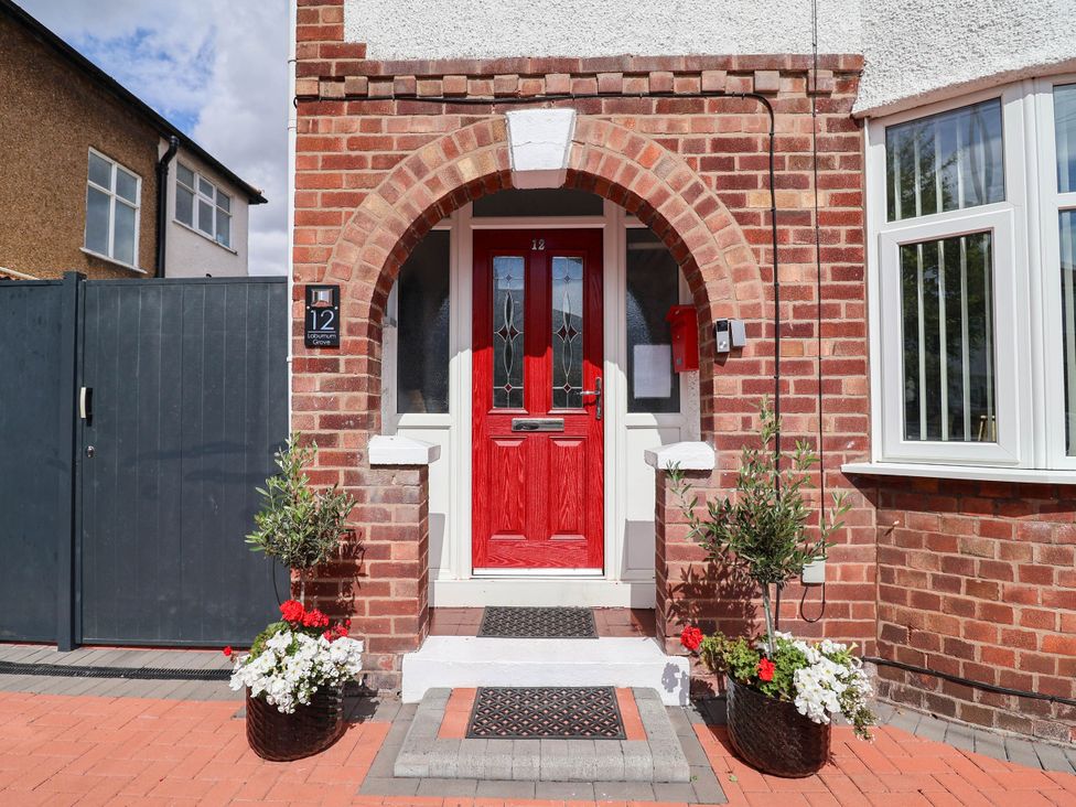 An entrance with a red door and flower pots at Laburnum house Ellesmere Port