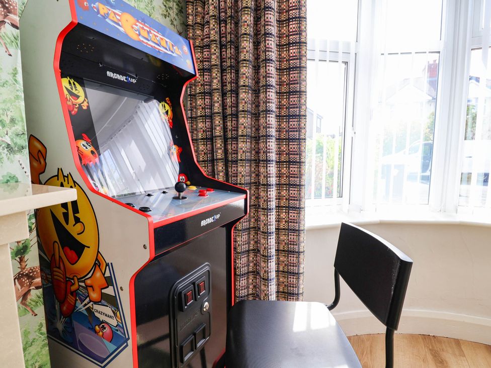 A game room with an arcade machine and chair at Laburnum house in Ellesmere Port