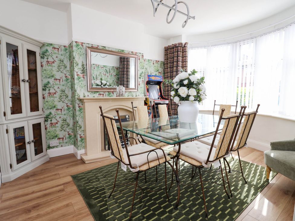 A dining room with a glass table and flower vase at Laburnum house Ellesmere Port