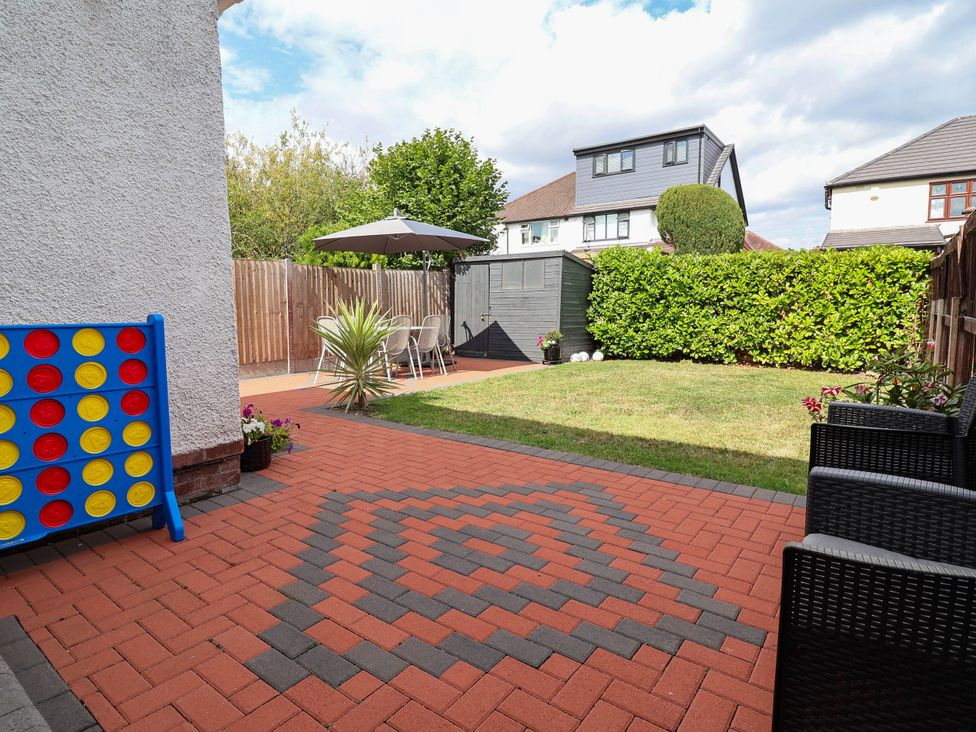 A garden with a patio, umbrella, table, and chairs at Laburnum house Ellesmere Port