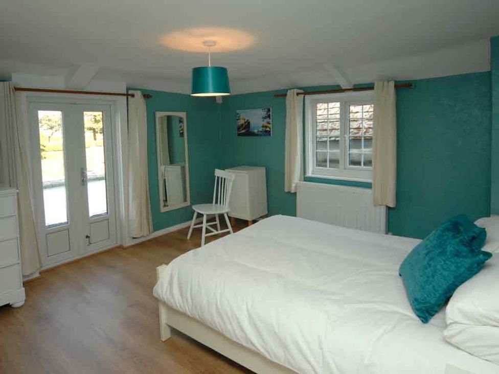 A bedroom with a bed and chair at Old Lyn Cottage in 