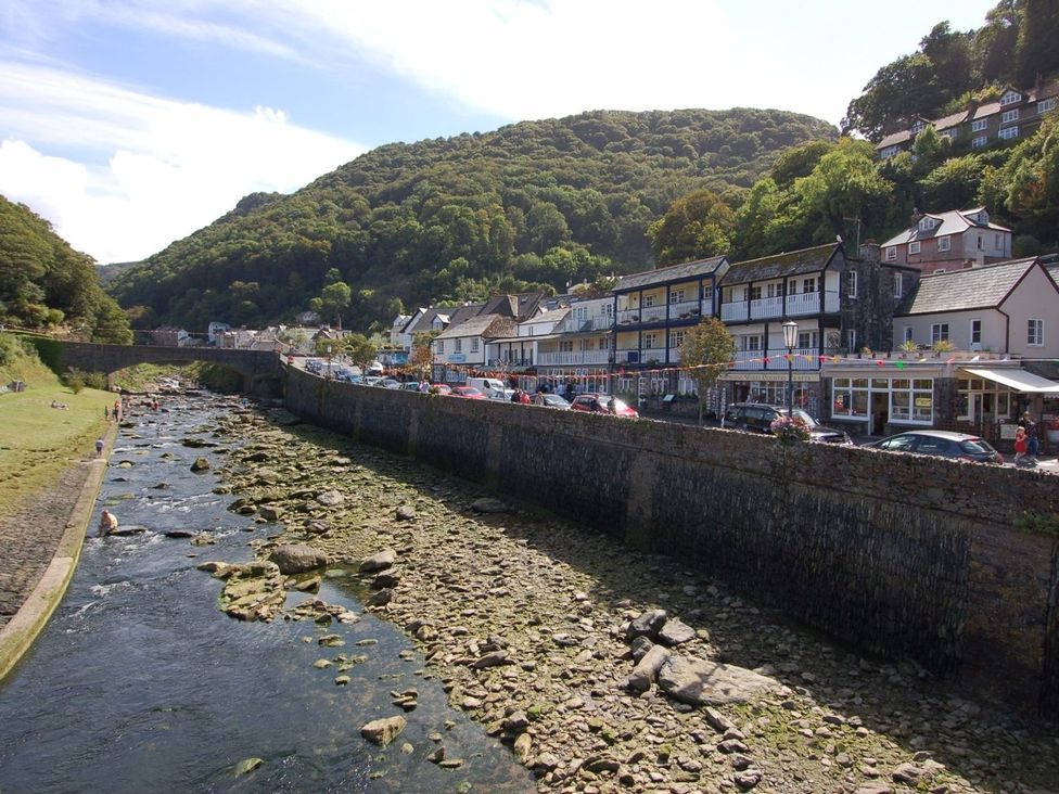 An outdoor view of a river with buildings and cars along the bank at Old Lyn Cottage in 