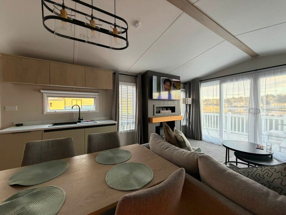 A living room with a dining table and kitchen area at Haggerston Castle - Lakeside Retreat in Berwick-upon-Tweed