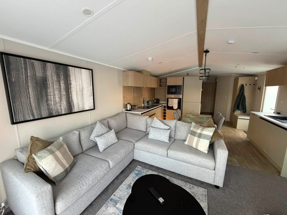 A living room with a sofa and kitchen area at Haggerston Castle - Lakeside Retreat Berwick-upon-Tweed