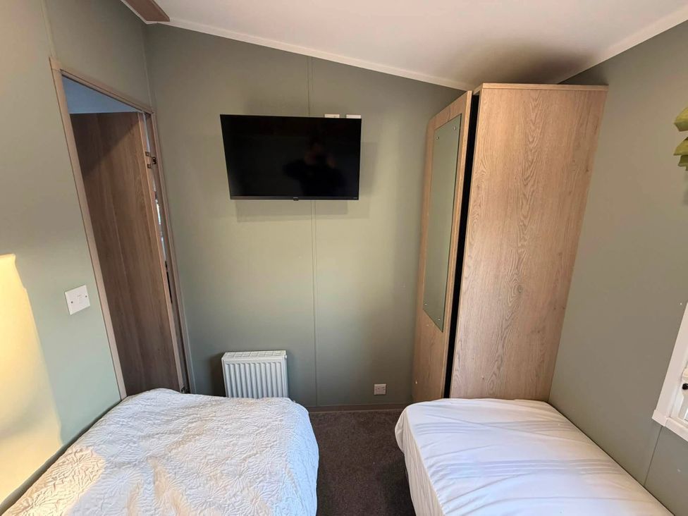 A bedroom with twin beds and a television on the wall at Haggerston Castle - Lakeside Retreat, Berwick-upon-Tweed