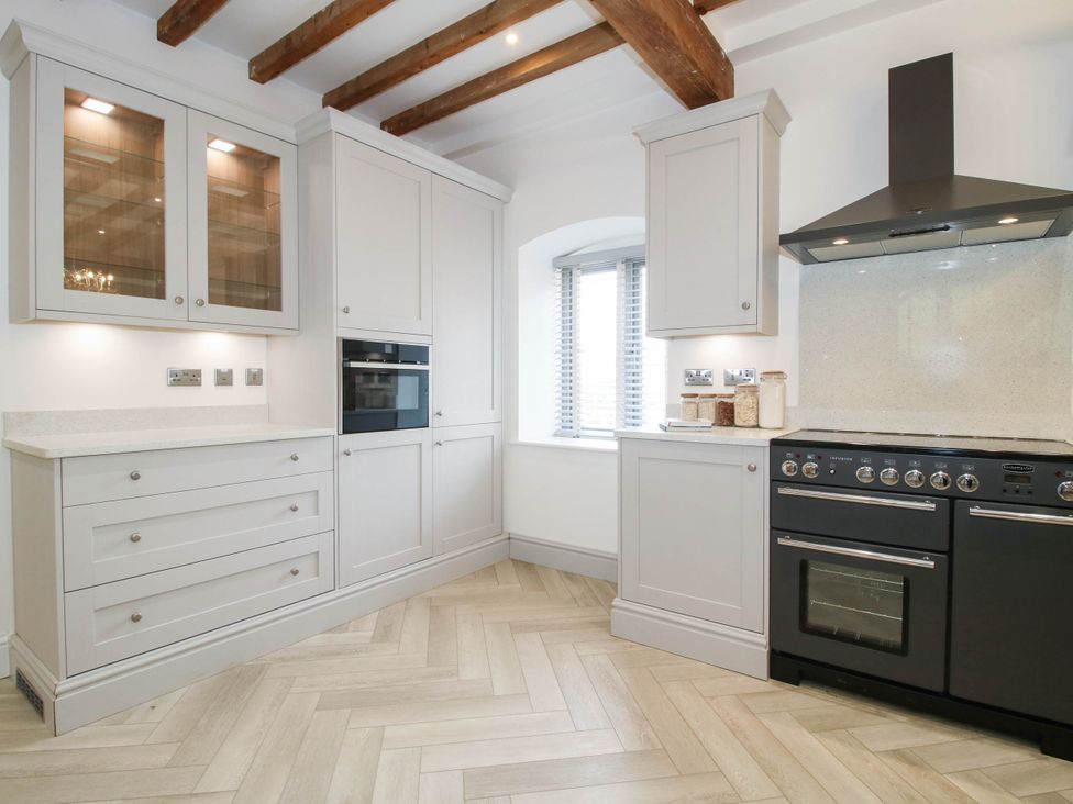 A kitchen with cabinets, oven, and window at The Hayloft in Birmingham