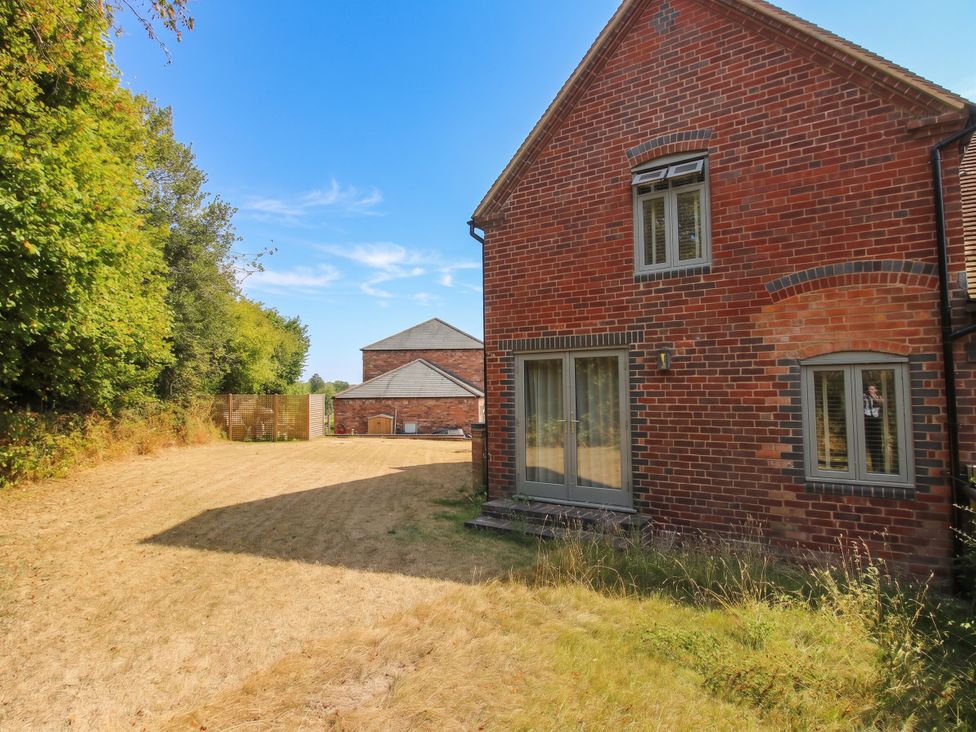 A garden with a brick house and trees at The Hayloft in Birmingham