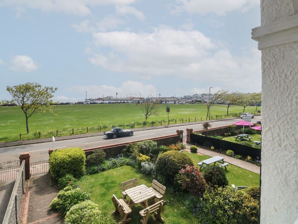 A view of a garden with a road and sea in the distance at Russell House in Paignton