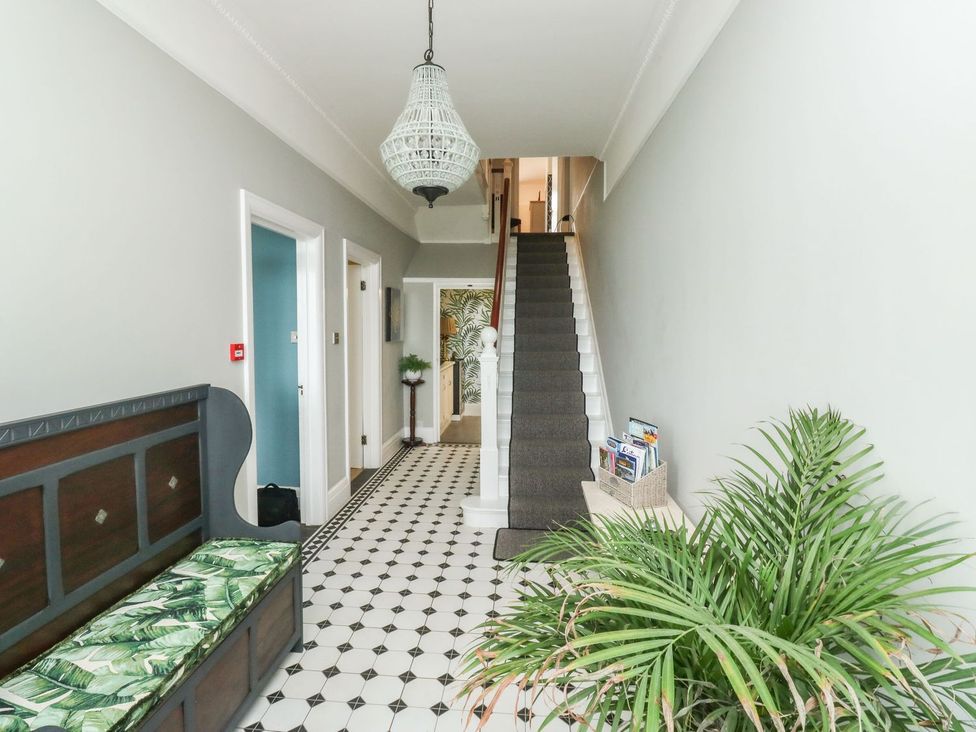 A hallway with a staircase and a bench at Russell House in Paignton