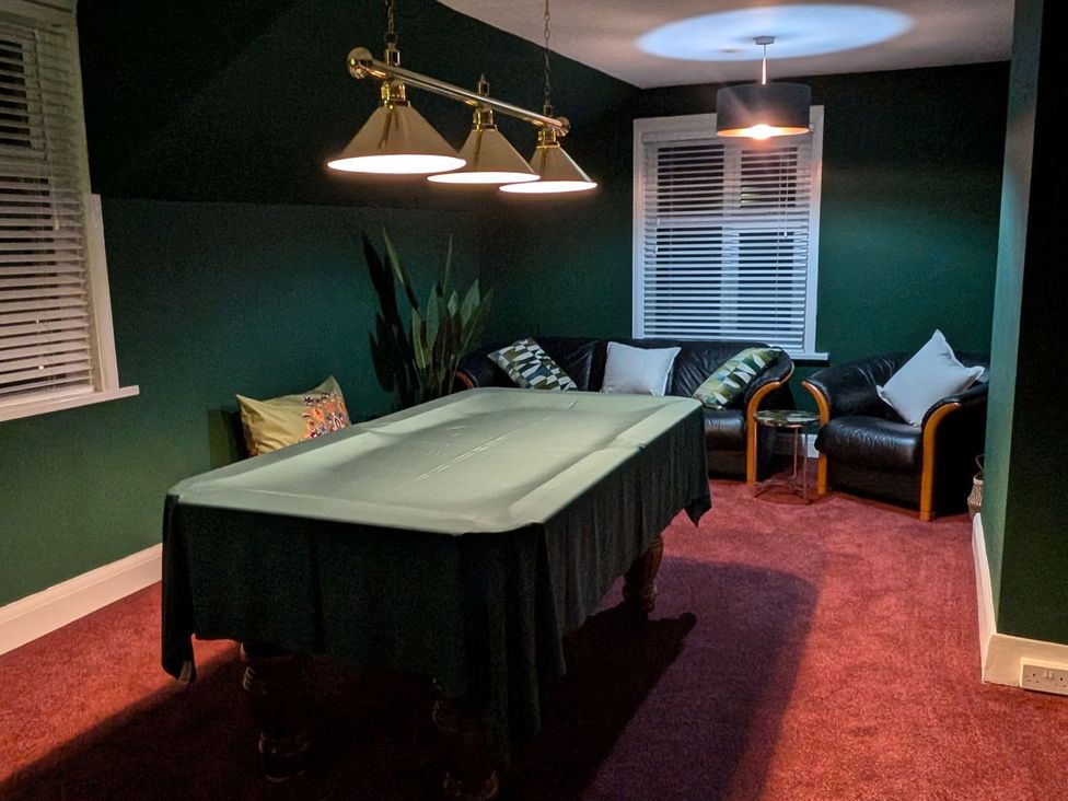 A game room with a pool table and couches at Russell House in Paignton