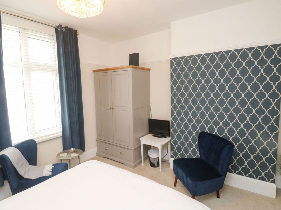 A bedroom with a wardrobe and armchair at Russell House in Paignton