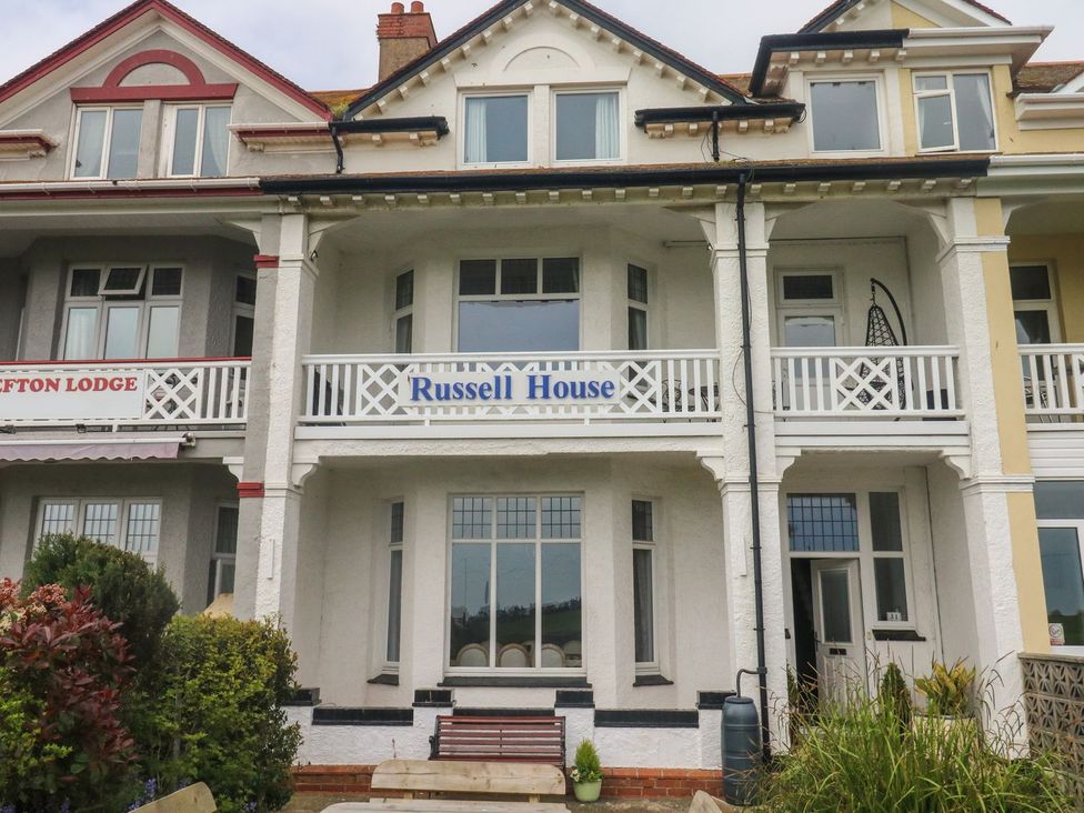 A facade of a house with a balcony and sign at Russell House in Paignton