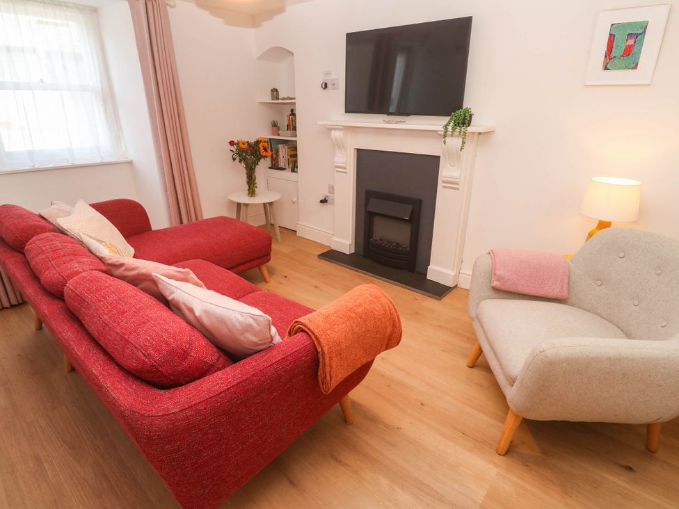 A living room with a sofa, armchair, television, and fireplace at Top Deck in St. Ives