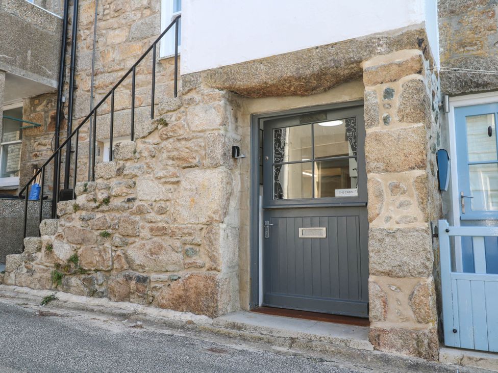 A stone wall with a grey door and stairs at The Cabin in St Ives