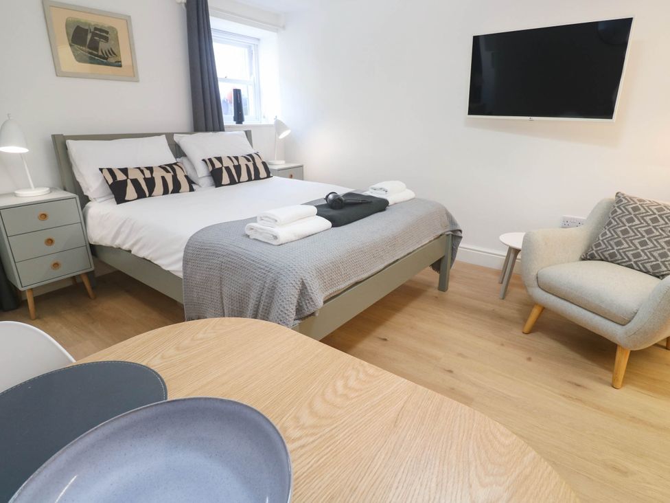 A bedroom with a bed and a chair at The Cabin in St Ives