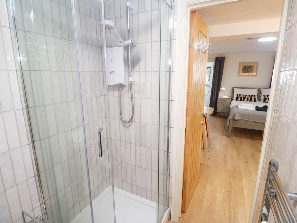 A bathroom with a shower and doorway leading to a bedroom at The Cabin St Ives