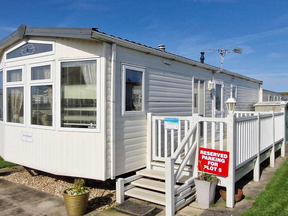 A mobile home with steps and a reserved parking sign at Beachcomber Cabin Dog Friendly Anderby Creek Lincolnshire