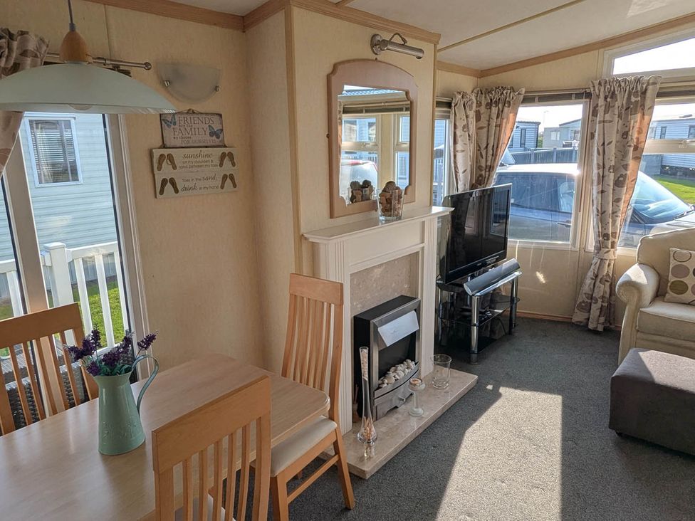 A living room with a fireplace and television at Beachcomber Cabin Dog Friendly Anderby Creek Lincolnshire