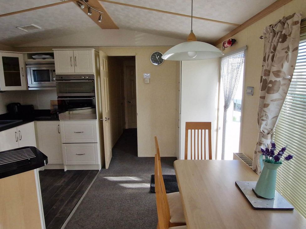 A kitchen with cabinets and a dining table at Beachcomber Cabin Dog Friendly Anderby Creek Lincolnshire