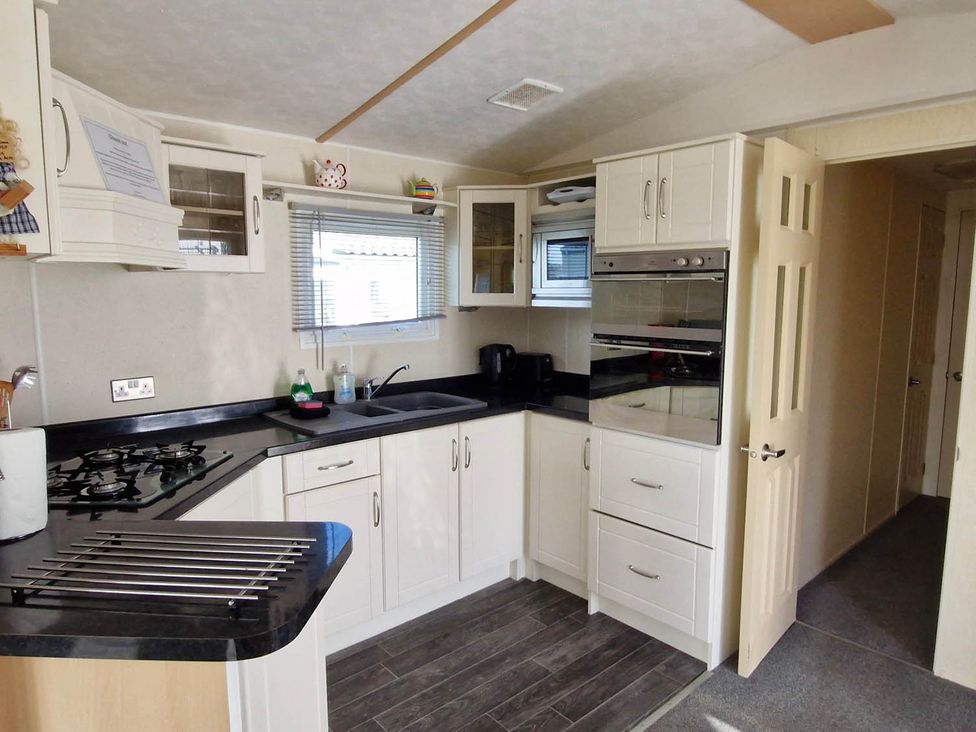 A kitchen with cabinets, sink, and stove at Beachcomber Cabin Dog Friendly Anderby Creek Lincolnshire