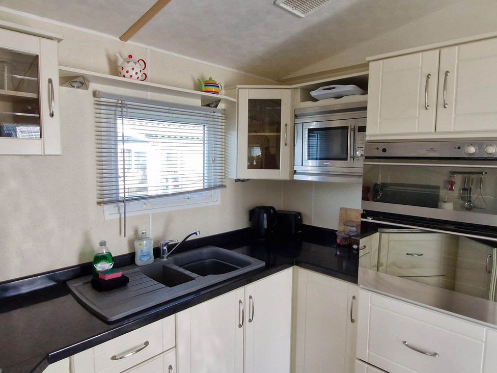 A kitchen with a sink, microwave, and cupboards at Beachcomber Cabin Dog Friendly Anderby Creek, Lincolnshire