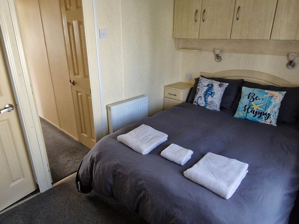 A bedroom with a bed and towels at Beachcomber Cabin Dog Friendly Anderby Creek Lincolnshire