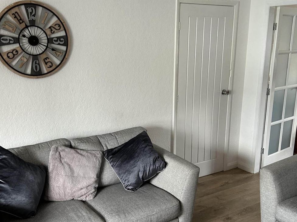 A living room with a clock and sofa at The Old Barn in Manchester