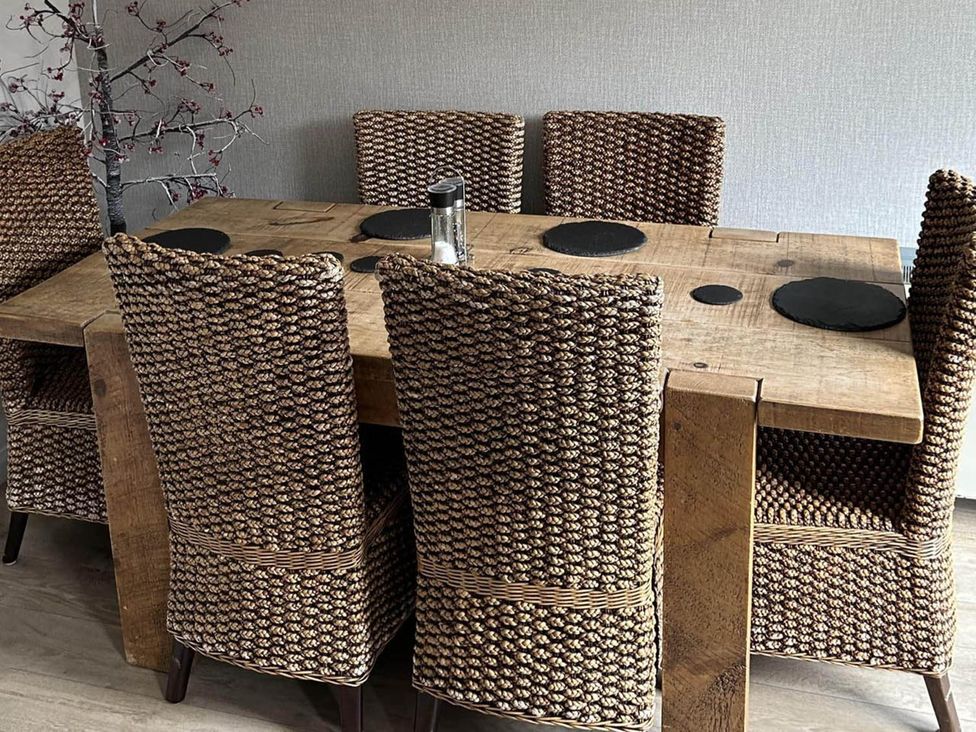A dining table with woven chairs and placemats at the property in location